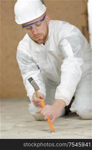 young builder removing tiles using a hammer and chisel