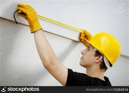 young builder with yellow tape measure, selective focus , natural soft light
