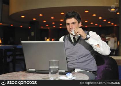 Young buisinessman drinking coffe while working on laptop