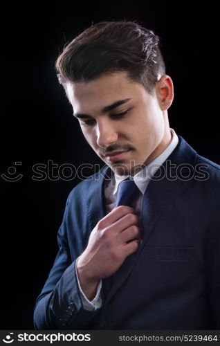 young businesman in suit in black background