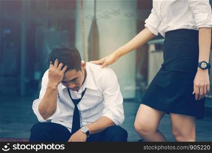 Young business asian man sitting and stress problem about job and woman coming to solace and helping at office.