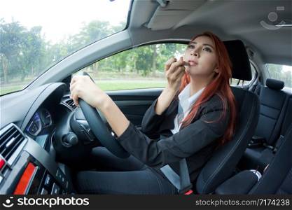 Young business asian woman applying makeup while in the car