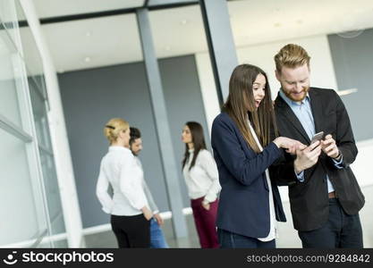 Young business couple looking at the phone in the office