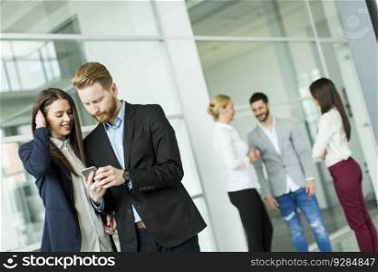 Young business couple looking at the phone in the office