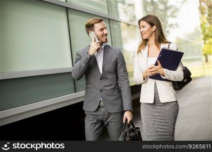 Young business couple walking and talking on the mobile phone outdoor