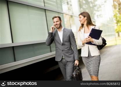 Young business couple walking and talking  on the mobile phone outdoor