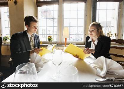 Young business couple with menus at restaurant table