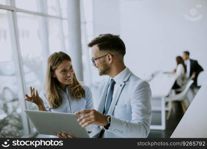 Young business couple working and discussing by laptop in the office in front of their team