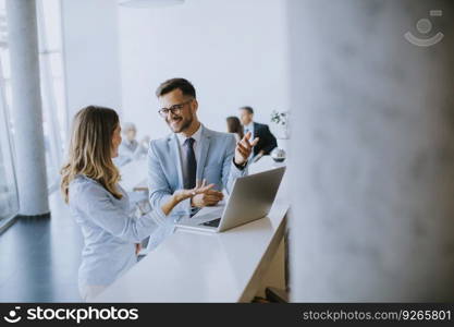 Young business couple working and discussing by laptop in the office in front of their team