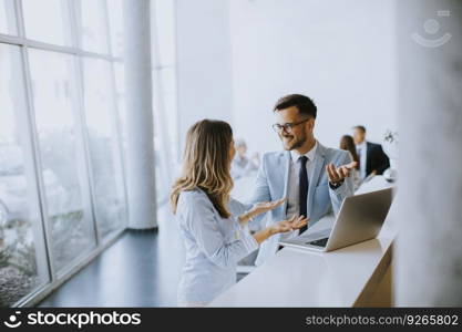 Young business couple working and discussing by laptop in the office in front of their team