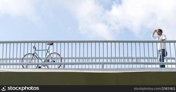 Young business male with sunglasses looking far away to a vintage bike on a bridge