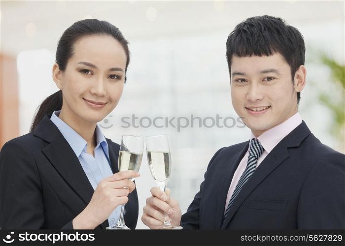 Young business man and woman toasting with champagne flutes