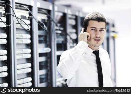 young business man computer science engeneer talking by cellphone at network datacenter server room asking for help and fast solutions and services