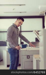 young business man copy documents on copy machine at modern startup office interior, casual clothes