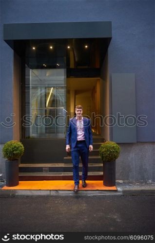 Young business man entering city hotel, looking for room, holding suitcases while walking on street