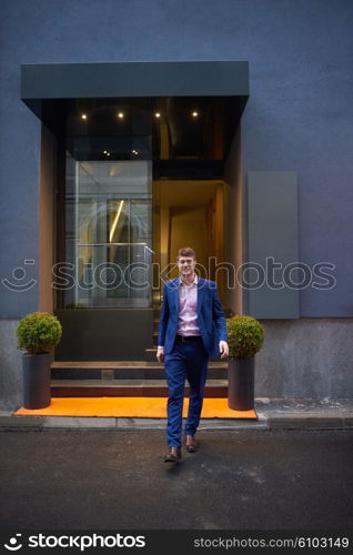 Young business man entering city hotel, looking for room, holding suitcases while walking on street