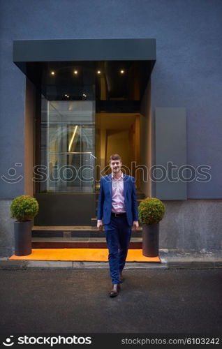 Young business man entering city hotel, looking for room, holding suitcases while walking on street