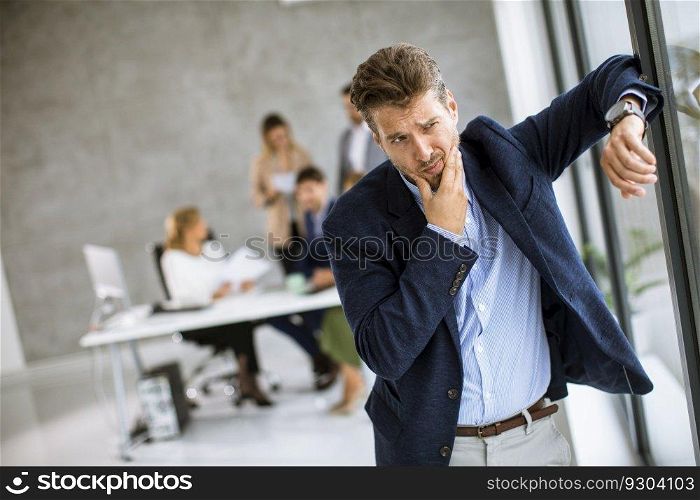 Young business man feeling exhausted and stand at his working place in office