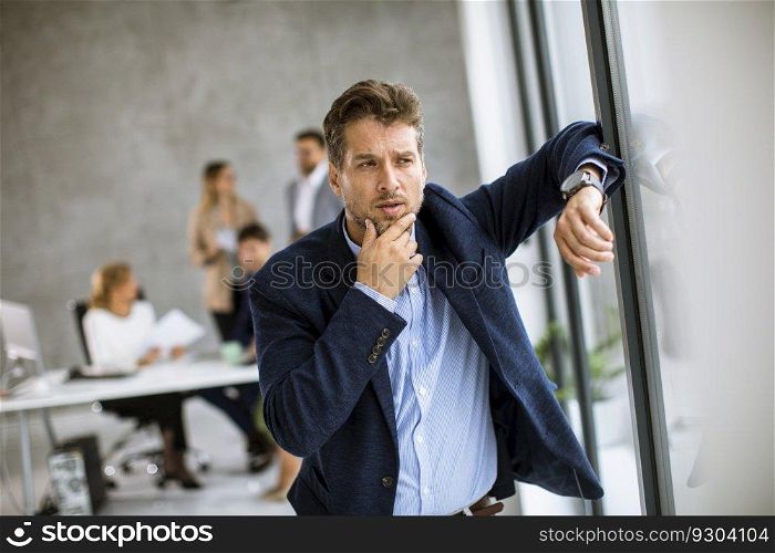 Young business man feeling exhausted and stand at his working place in office