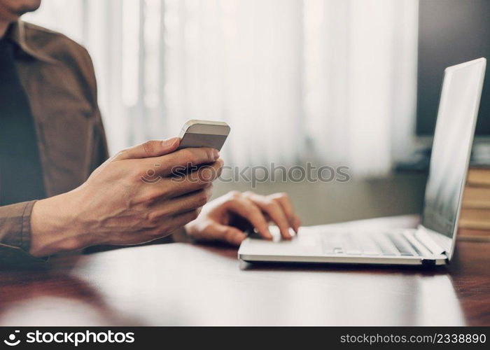 Young business man hand holding and using smartphone in the office with sunlight. Vintage toned filter.