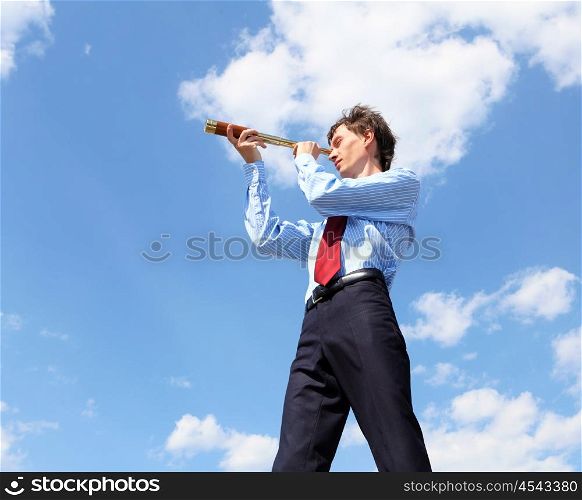 young business man in a blue shirt and red tie against the blue sky looks through a telescope. a symbol of leadership, success and freedom.