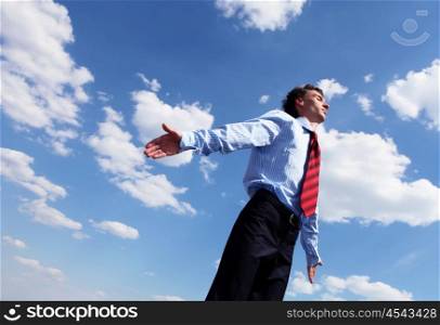young business man in a blue shirt and red tie against the blue sky. a symbol of leadership, success and freedom.