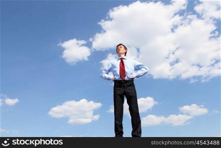 young business man in a blue shirt and red tie against the blue sky. a symbol of leadership, success and freedom.