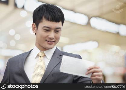 Young business man looking at flight ticket