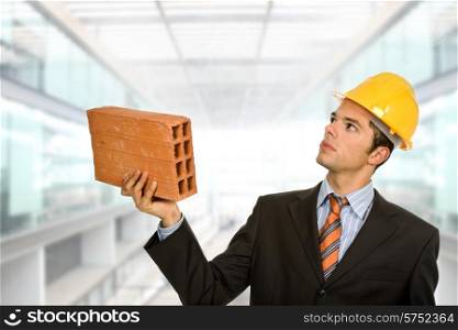 young business man looking up, with a brick