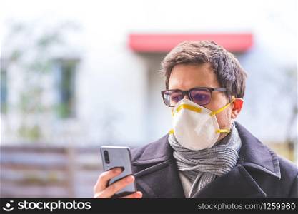 Young business man outdoors with a breathing mask and smartphone. Flue and corona season.
