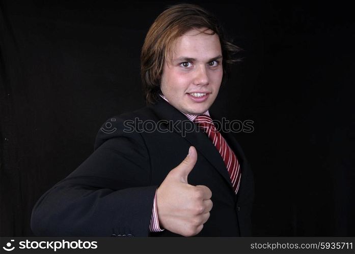 Young business man showing thumb up on black background