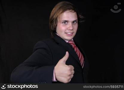 Young business man showing thumb up on black background