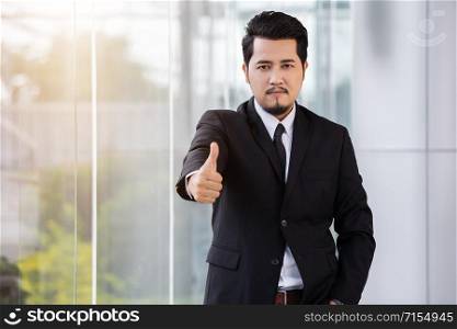 young business man showing thumbs up sign in office