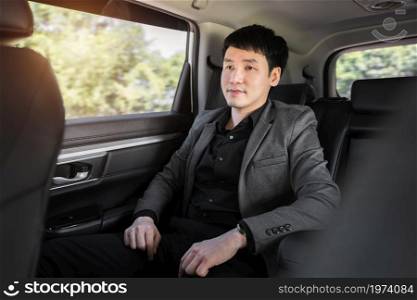 young business man sitting at the back seat of car