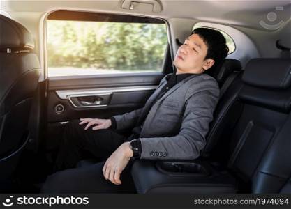 young business man sleeping while sitting in the back seat of car
