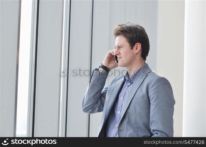 young business man talk by cellphone over bright window in big hall