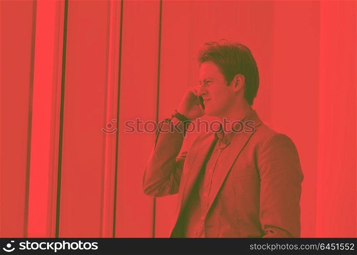 young business man talk by cellphone over bright window in big hall DUO TONE
