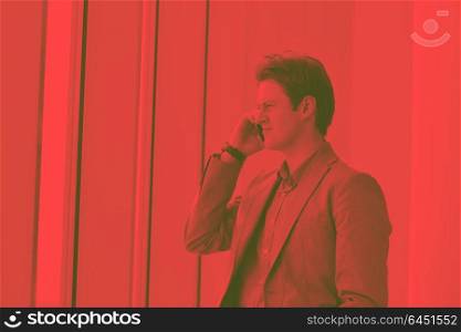 young business man talk by cellphone over bright window in big hall DUO TONE
