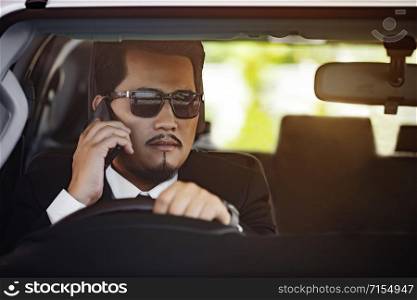 young business man talking with mobile phone and driving a car