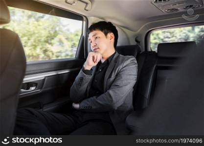 young business man thinking while sitting in the back seat of car