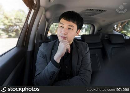 young business man thinking while sitting in the back seat of car