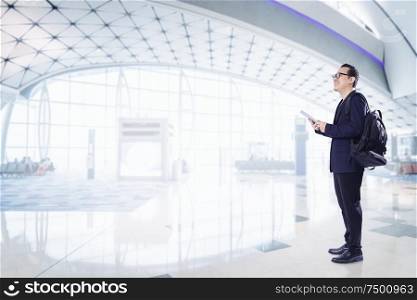 Young business man using digital pad smiling happy inside airport waiting hall .