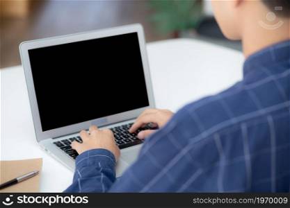 Young business man using laptop computer blank screen on desk at home, businessman work on notebook to internet online copy space for your text message, male typing keyboard, communication concept.