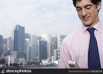 Young business man using mobile phone, office buildings in background