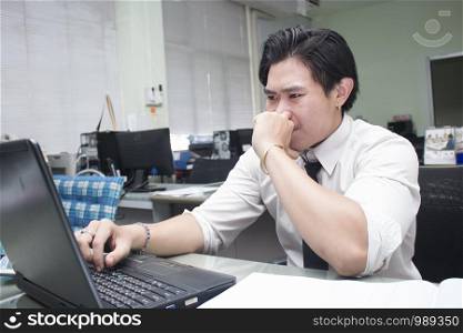 young business man working at desk on laptop looking serious