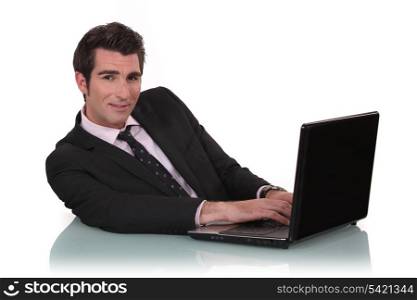 Young business mat sat at desk with laptop