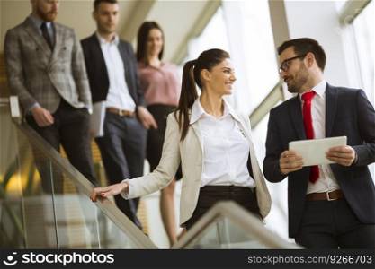 Young business partners analyze the business results while walking down the stairs in modern office
