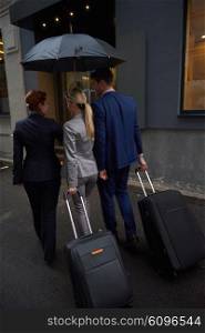 Young business people couple entering city hotel, looking for room, holding suitcases while walking on street