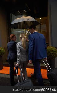 Young business people couple entering city hotel, looking for room, holding suitcases while walking on street