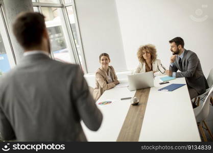 Young business people sitting at meeting table in conference room discussing work and planning strategy